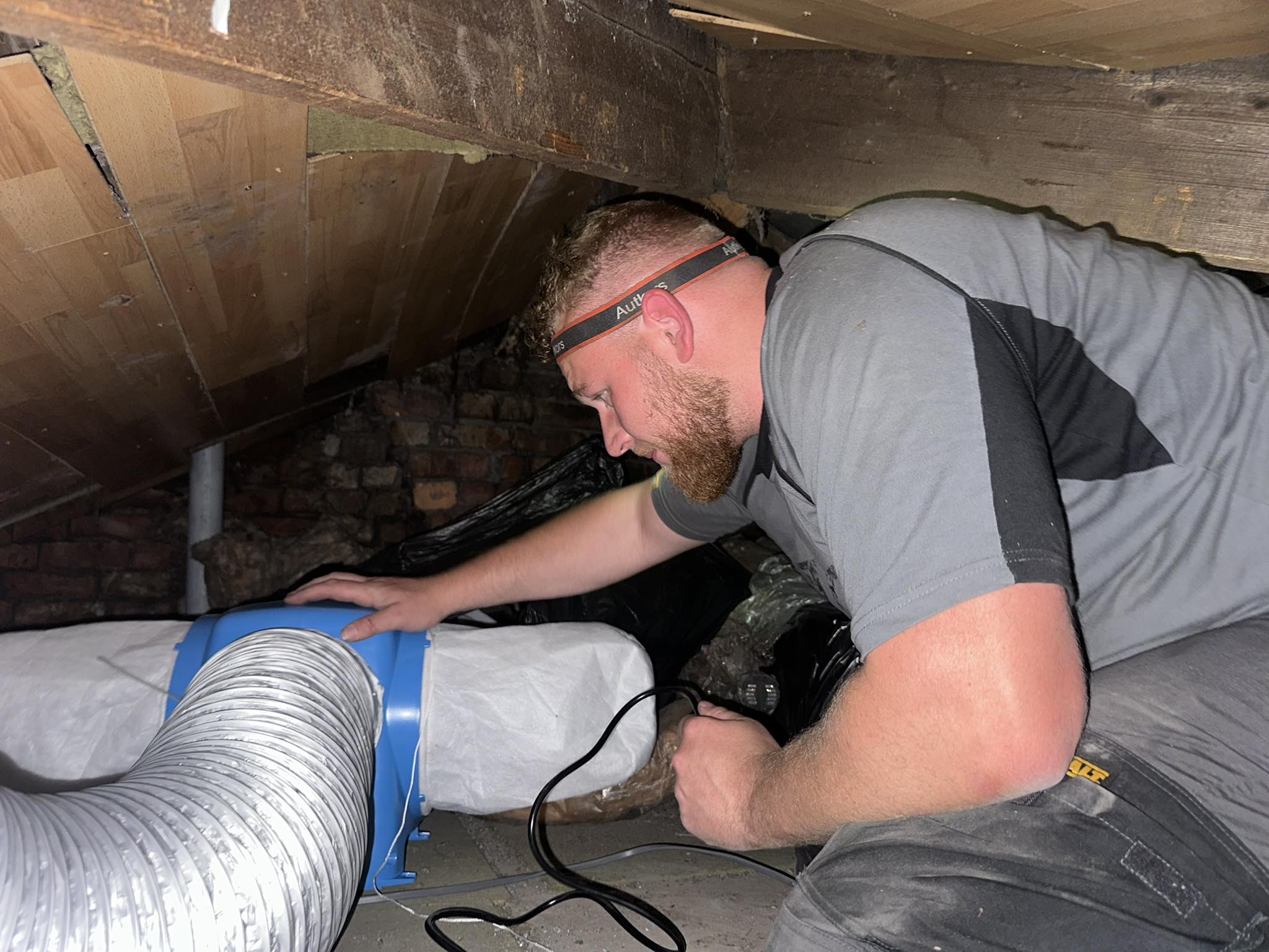 Technician installing ductwork in crawl space