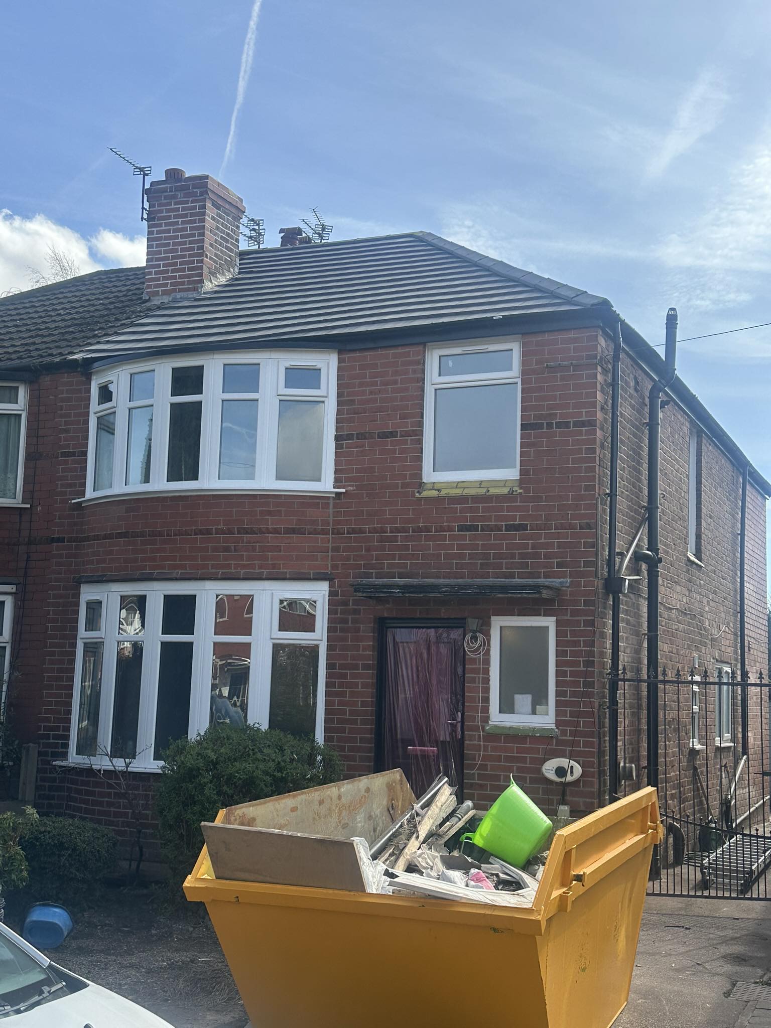 Red brick semi-detached house with yellow skip bin