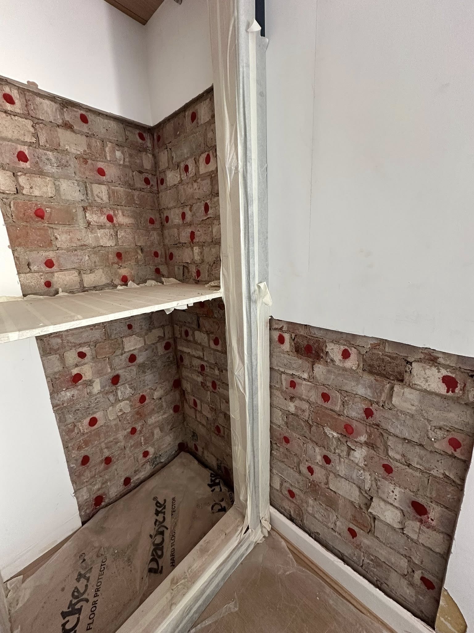 Exposed brick wall with red paint spots under construction