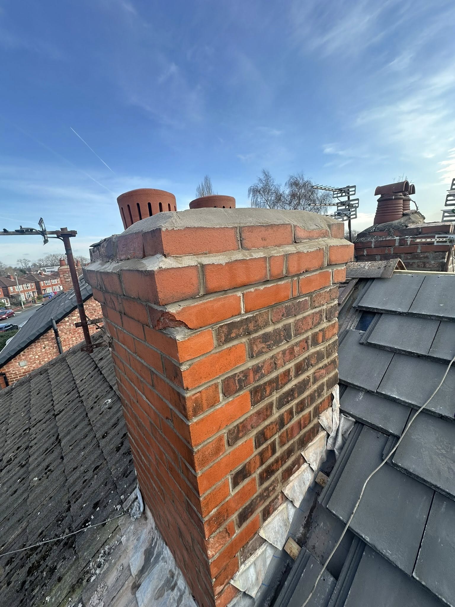 Brick chimney on residential roof with slate tiles