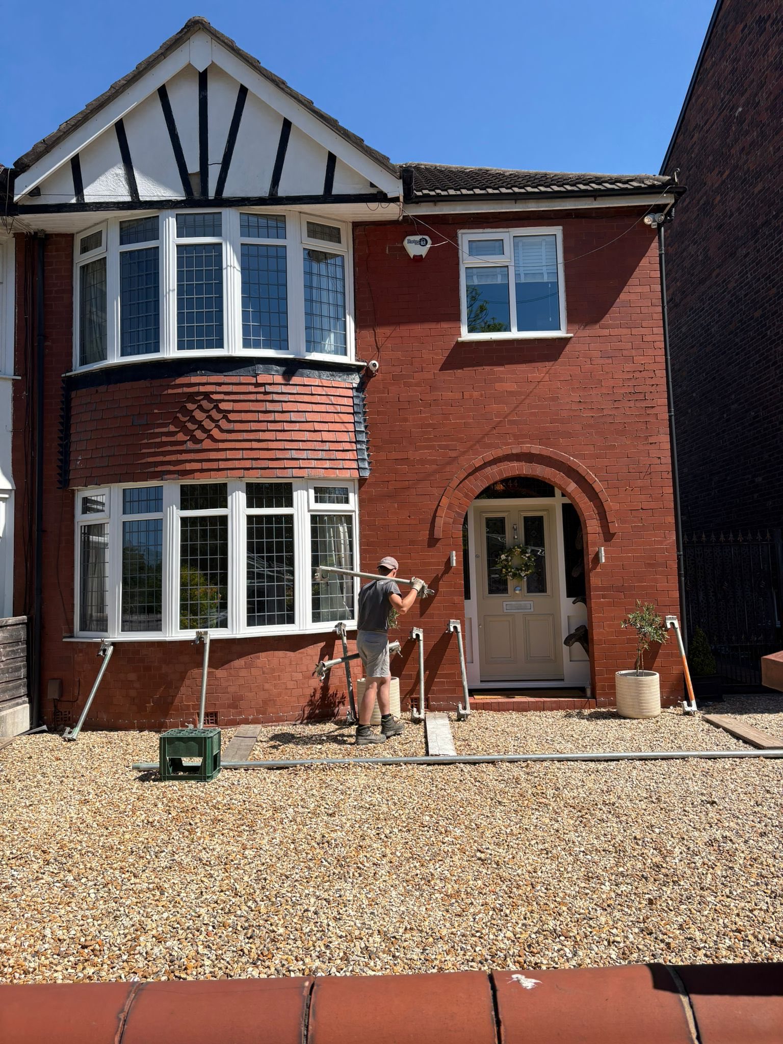 Worker painting exterior brick house facade preparation