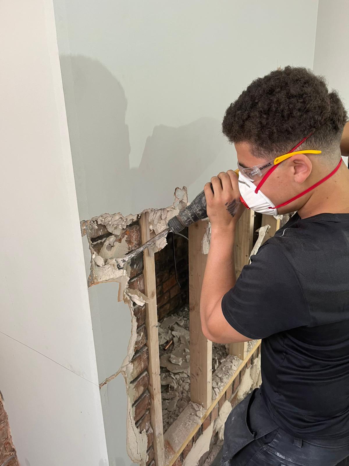 Worker using power tool to remove drywall from wall