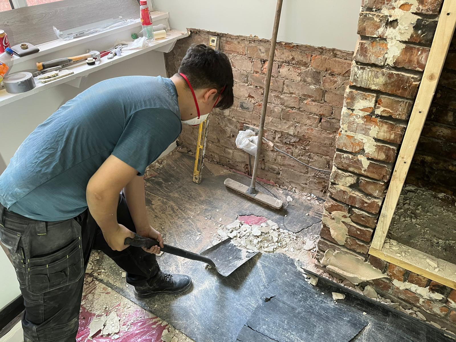 Worker scraping debris from floor during renovation