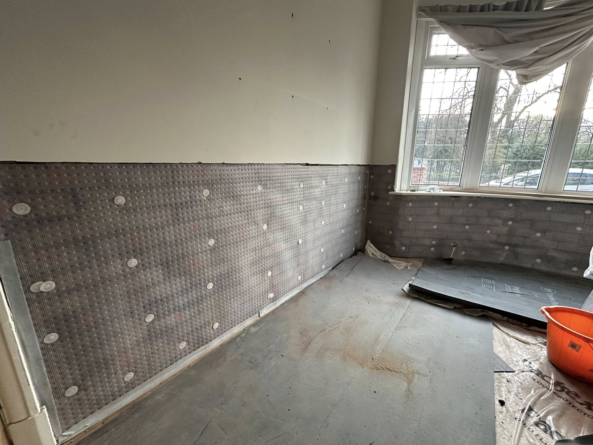 Interior room with protective wall sheeting and bare floor
